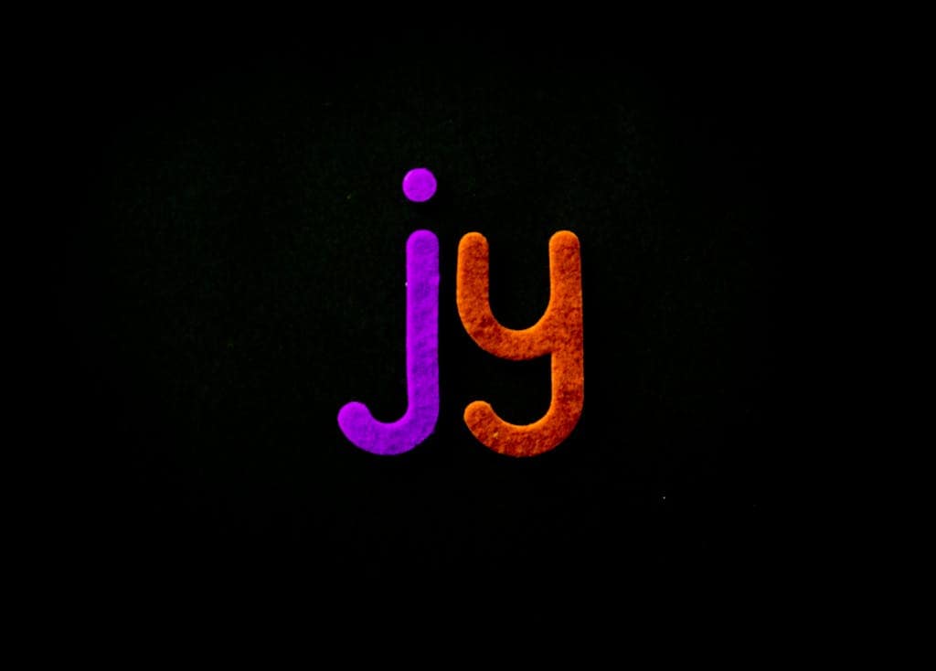 Bright and colorful letters 'jy' pop against a black background, creating a striking visual contrast.