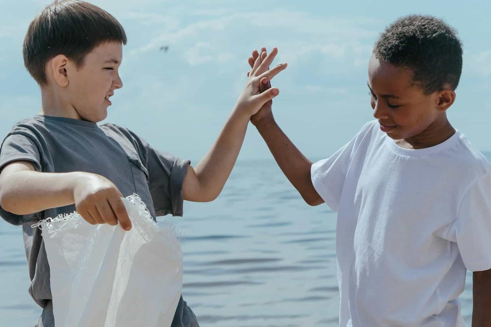 Two diverse children cleaning up the seaside, promoting environmental volunteerism and teamwork.