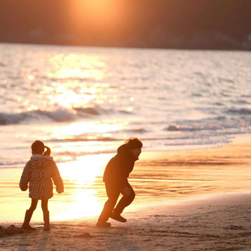 Two kids enjoying a playful sunset outing at the beach.