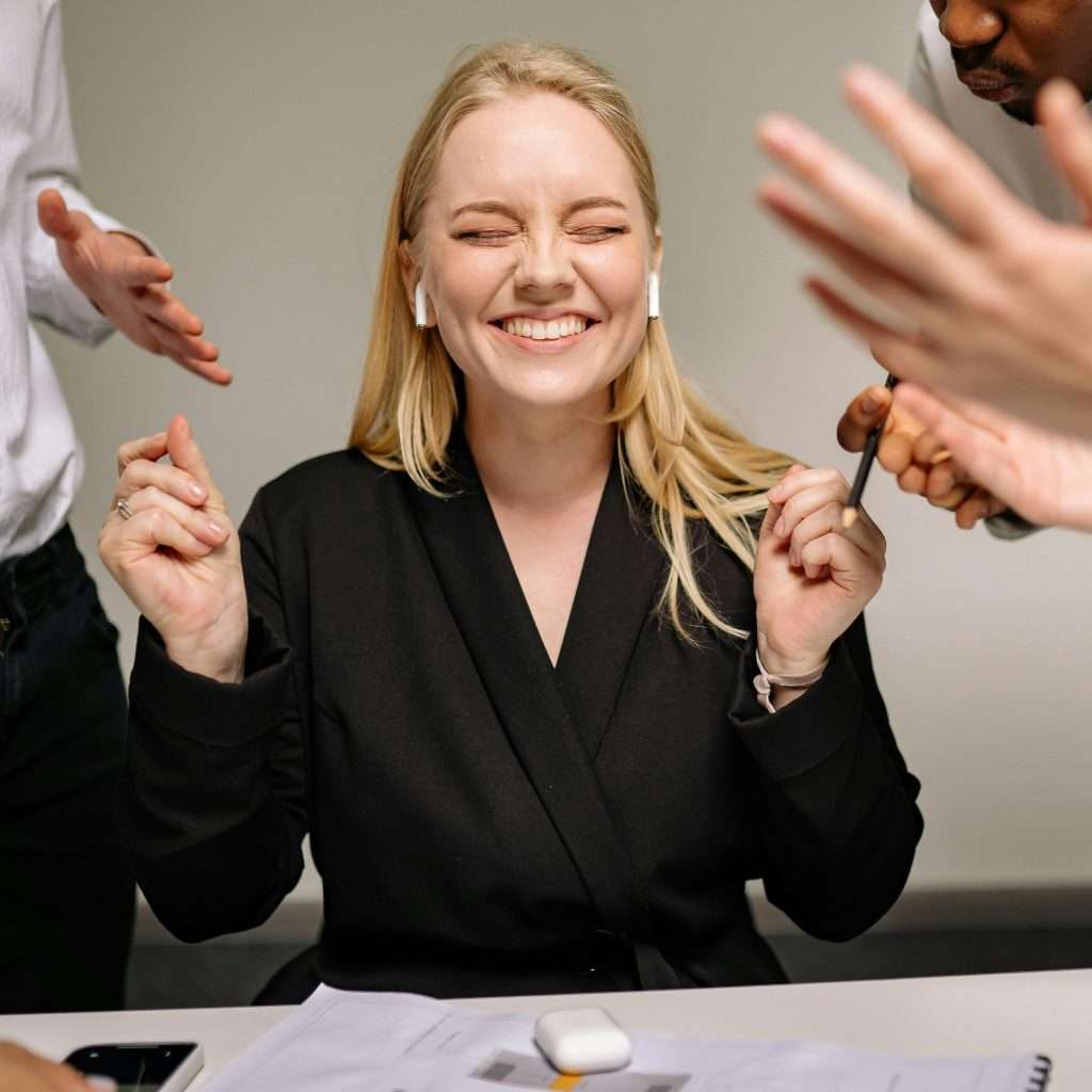 Happy woman smiling with closed eyes and earpods in a business meeting.