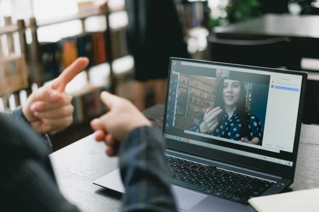 Zwei taubstumme Menschen sitzen vor einem Laptop und unterhalten sich per Video über Zeichensprache.