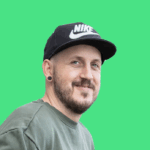 Benny Schey hat grüne Augen und einen Bart. Etwas mehr als ein 3-Tage-Bart. Er trägt eine schwarze Mütze von Nike und einen grauen Pulli.