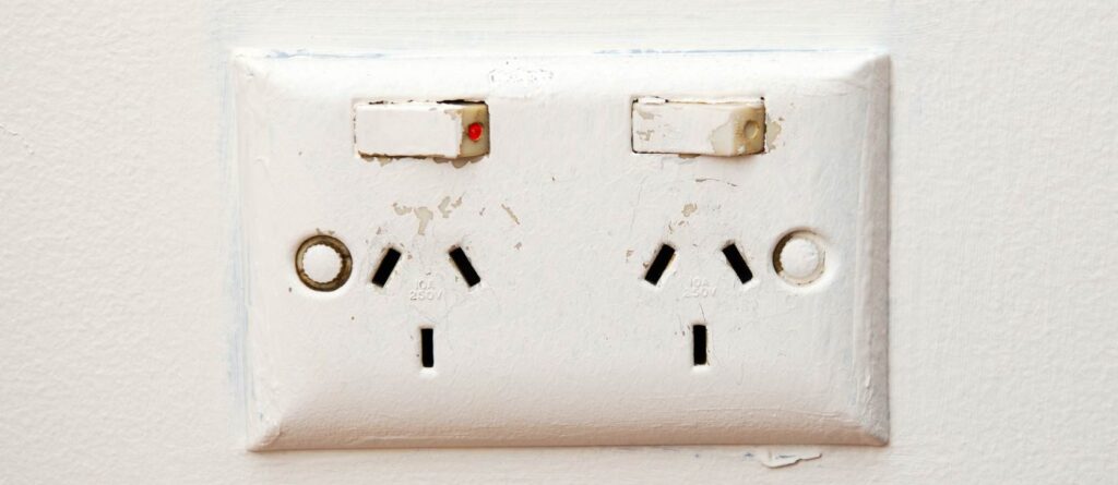Power outlet with two sockets on a white wall, close-up.