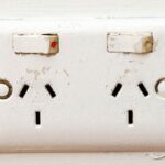 Power outlet with two sockets on a white wall, close-up.