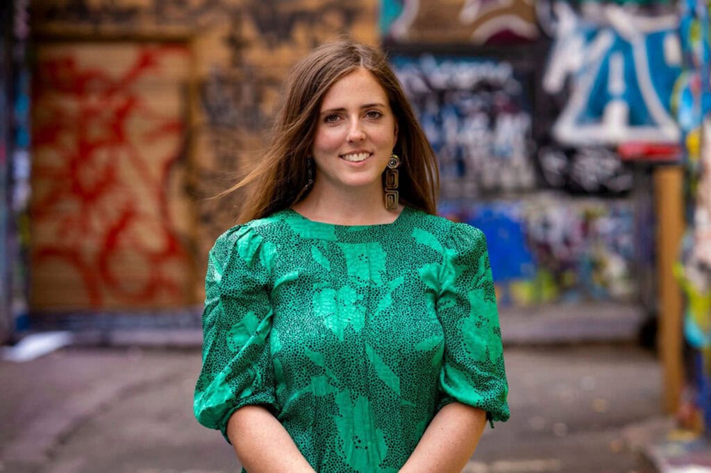 Green snake print dress worn by a woman in an urban graffiti setting, showcasing fashion and street.