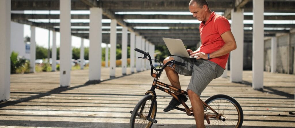 Electric bike rider using a laptop at a solar-powered facility in Australia.