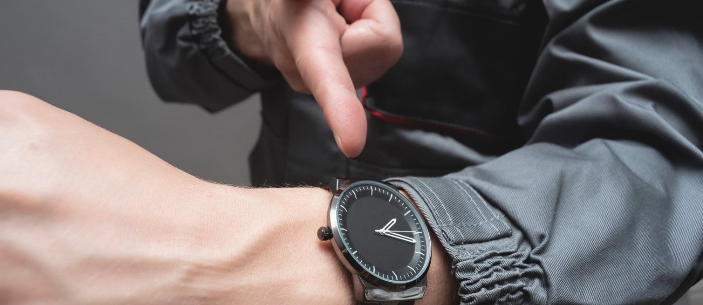 Wristwatch with black dial and silver case on person's wrist, close-up shot.