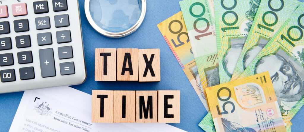 Tax time concept with calculator, Australian dollar notes, and "TAX TIME" blocks.