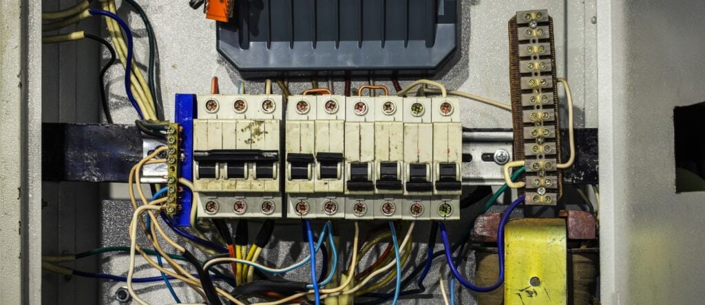 High-voltage electrical circuit breaker with wiring and components inside an electrical panel.