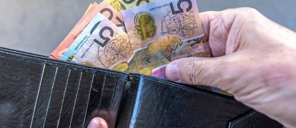 A wallet with Australian $50 and $5 banknotes being taken out.