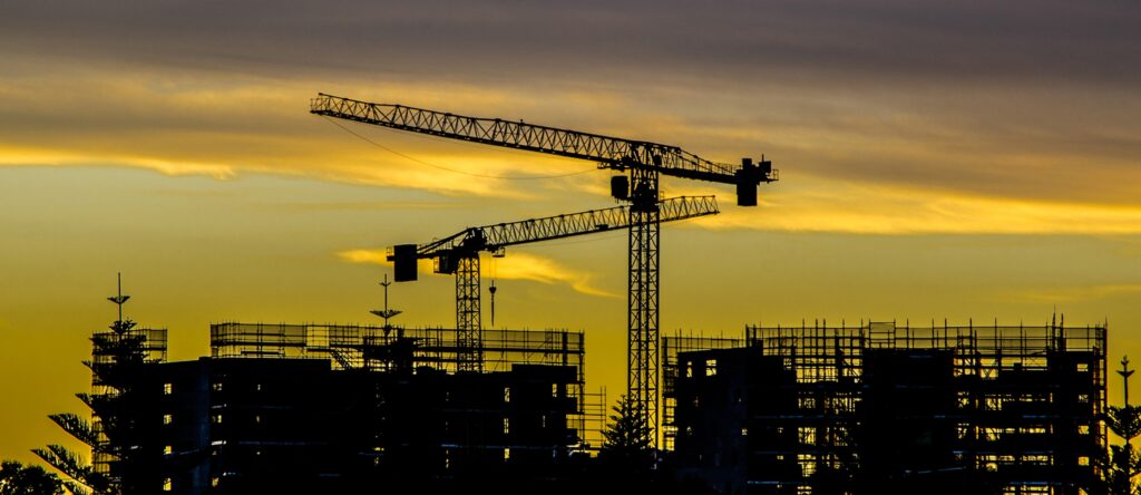 Construction site with cranes and building frameworks at sunset in Australia.