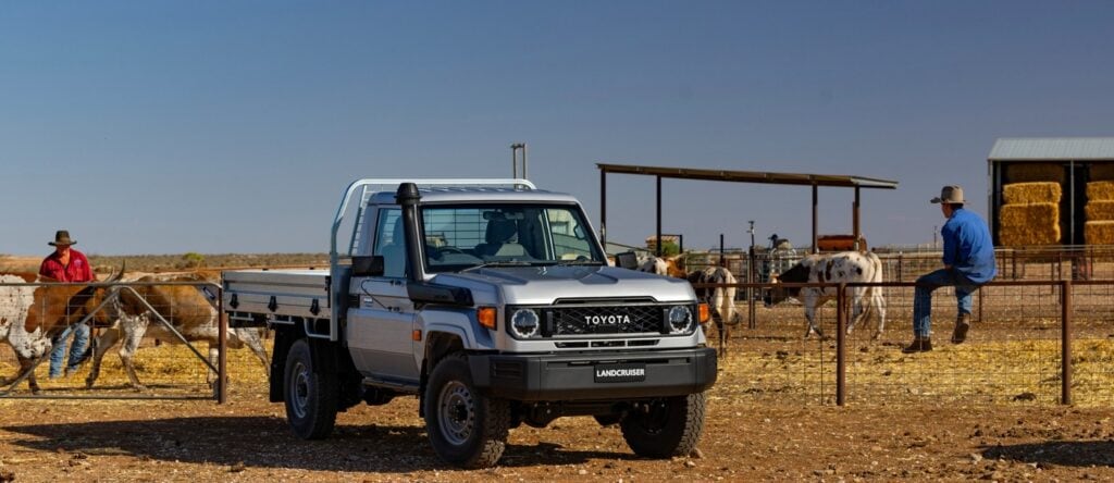 Toyota Land Cruiser ute on a farm with people and horses in the background, rural landscape, clear s.
