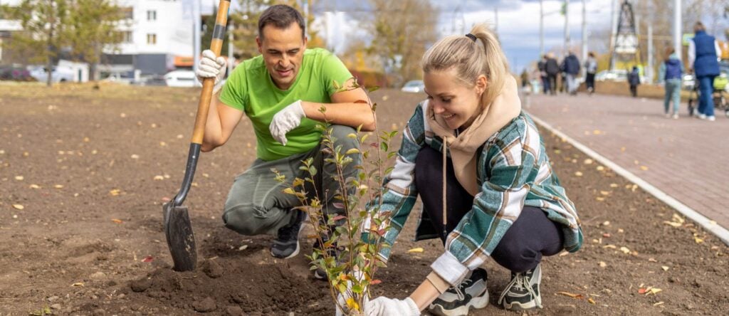 Eco-friendly community planting event with volunteers planting young trees in an urban park.