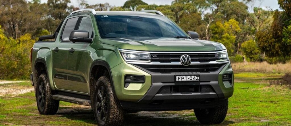 All-Terrain Volkswagen Amarok pickup truck in lush outdoor setting with trees and grass.