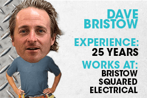 A man with curly hair wearing a blue shirt, standing confidently with hands on hips.