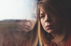 Moody woman leaning against window