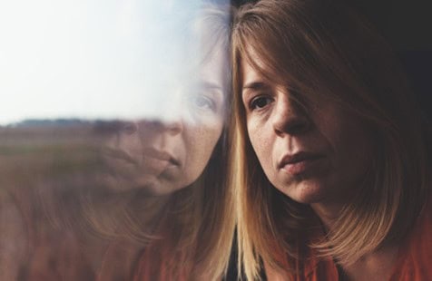 Moody woman leaning against window