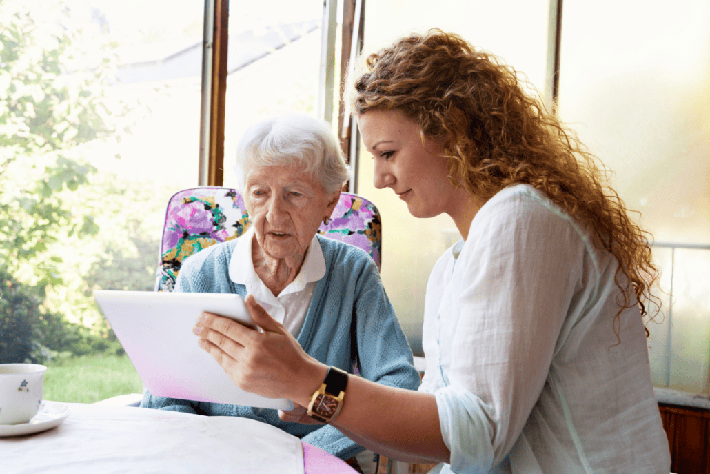 brunette woman holding ipad for elderly woman