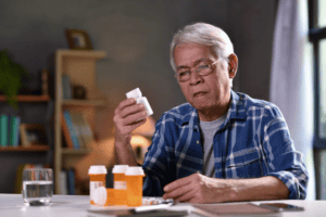 man sitting examining one pill bottle against three others