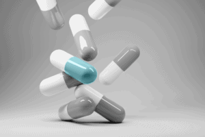multiple grey and white pill capsules with one white and blue capsule