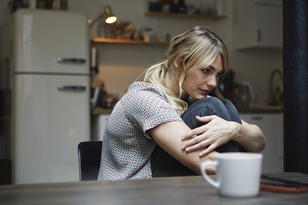 woman sitting at table with arms wrapped around legs