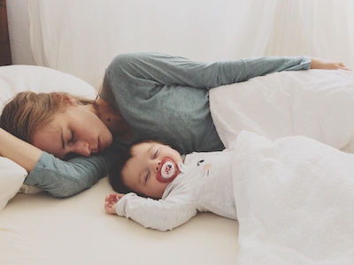 baby laying next to mother in bed