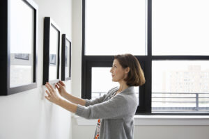 woman hanging up black square frame