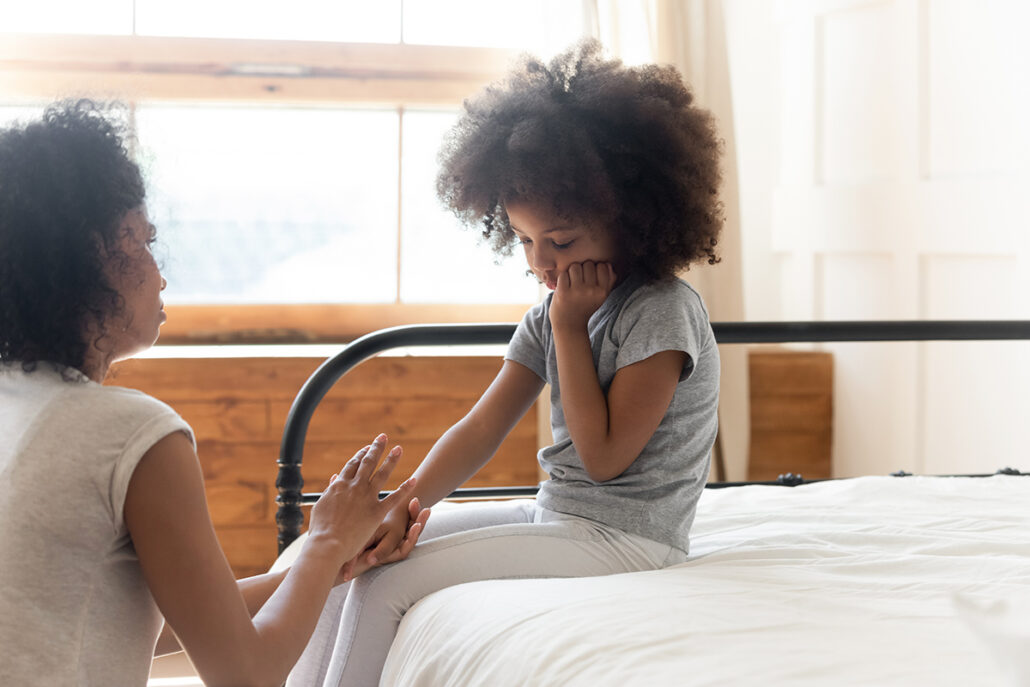 mom holding daughters hand on bed