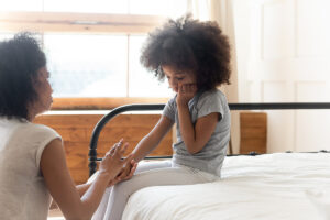 mom holding daughters hand on bed