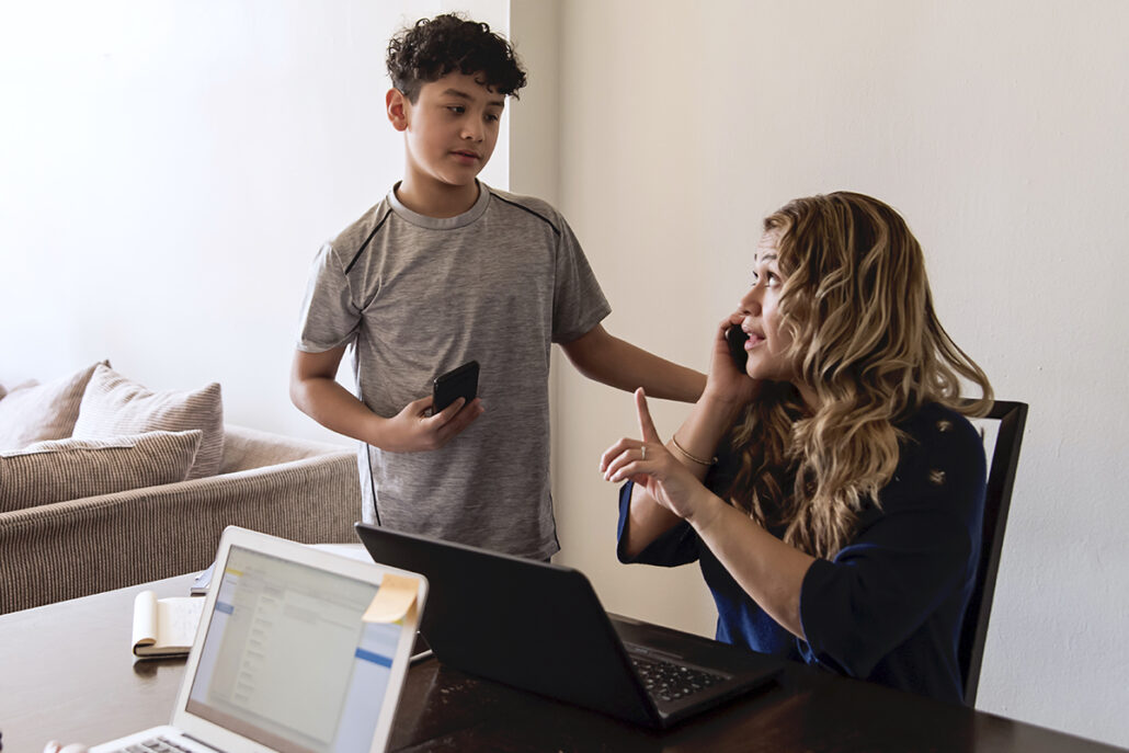 mother telling her son to wait a minute while she is on the phone