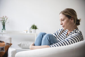 woman sitting on couch with hands around legs