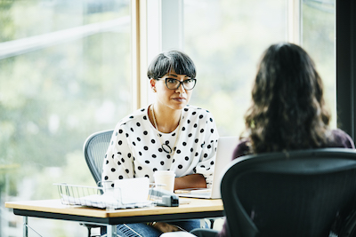 two woman sitting discussing over coffee