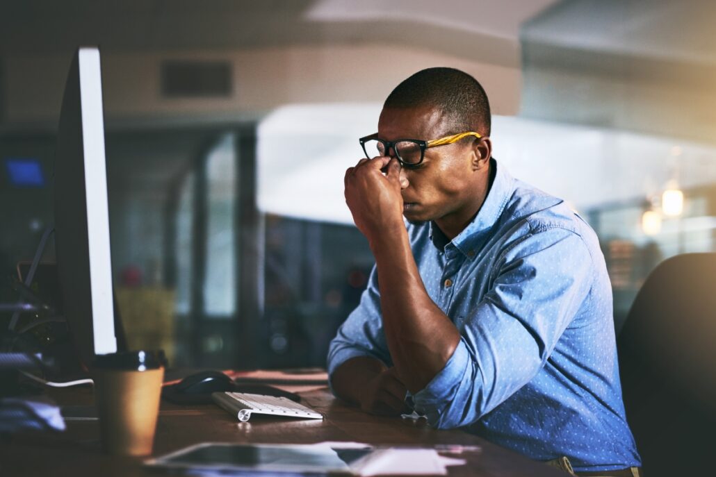 man sitting at desk leaning into hands