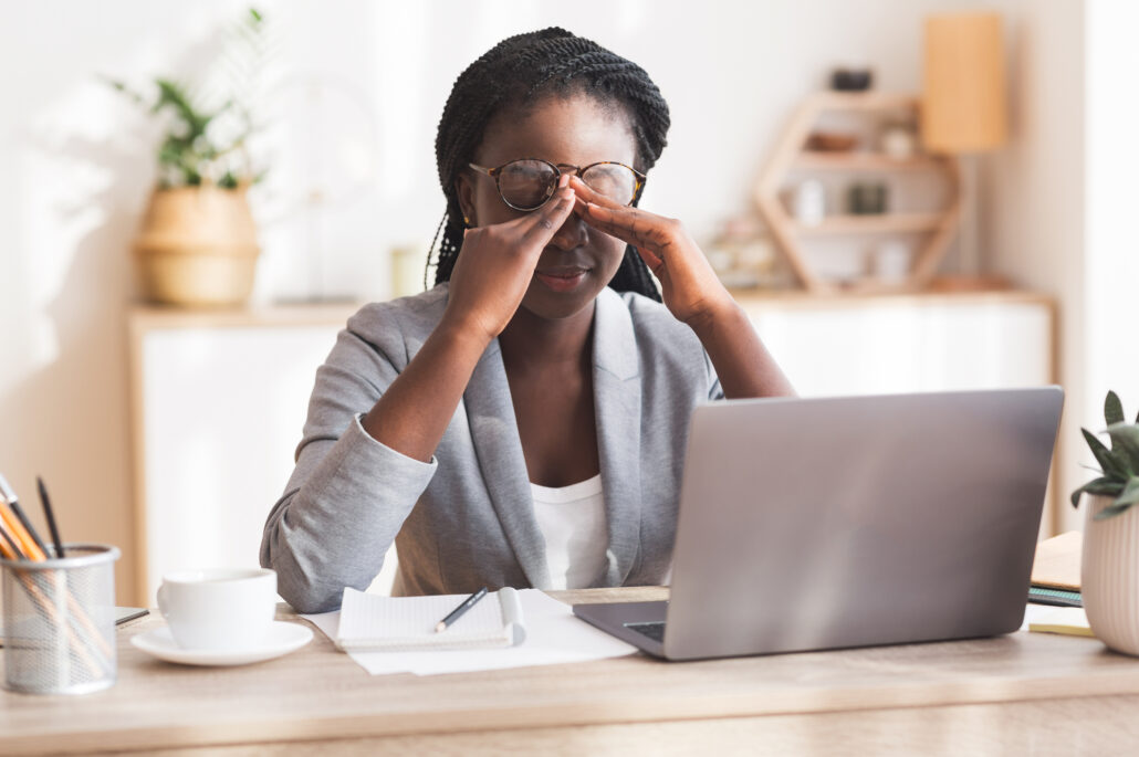 girl sitting at desk looking at computer with hands in between eyes