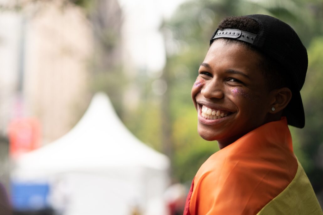 person smiling while wearing pride flag