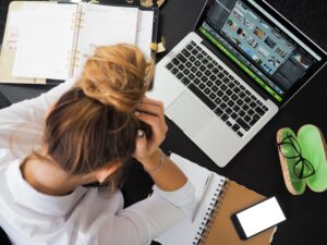 girl staring down at computer with notebooks open