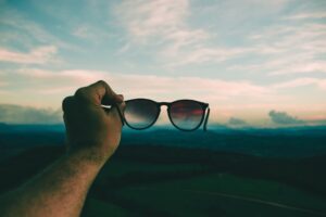 person holding sunglasses at sunset