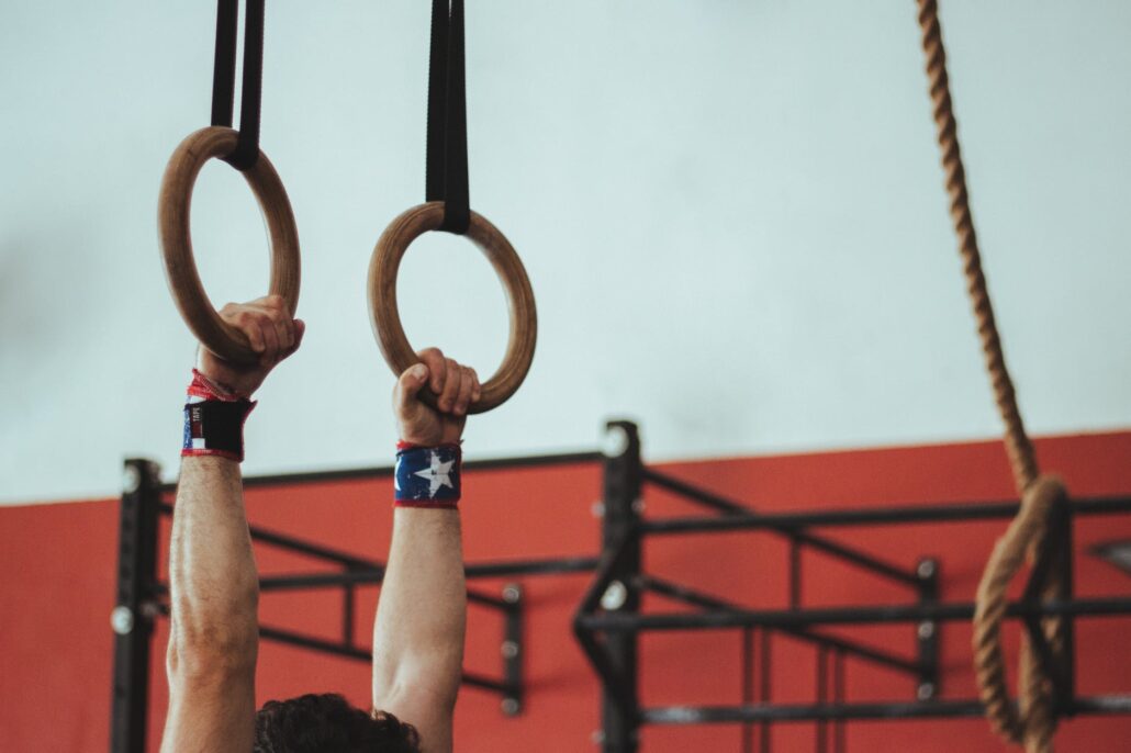 man hanging from rings with star wristbands