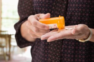 torso shot of well-dressed person pouring pills into hand