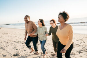 4 older women walking on beach to offset the hidden costs of aging
