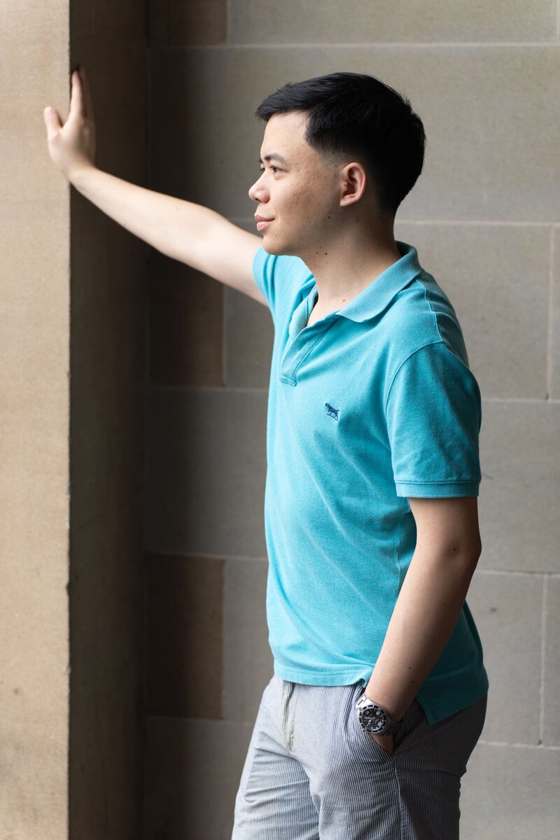 Ext: Young Asian man in a blue shirt having a natural light dating portrait taken with dating app photographer Georgie Greene in Sydney NSW