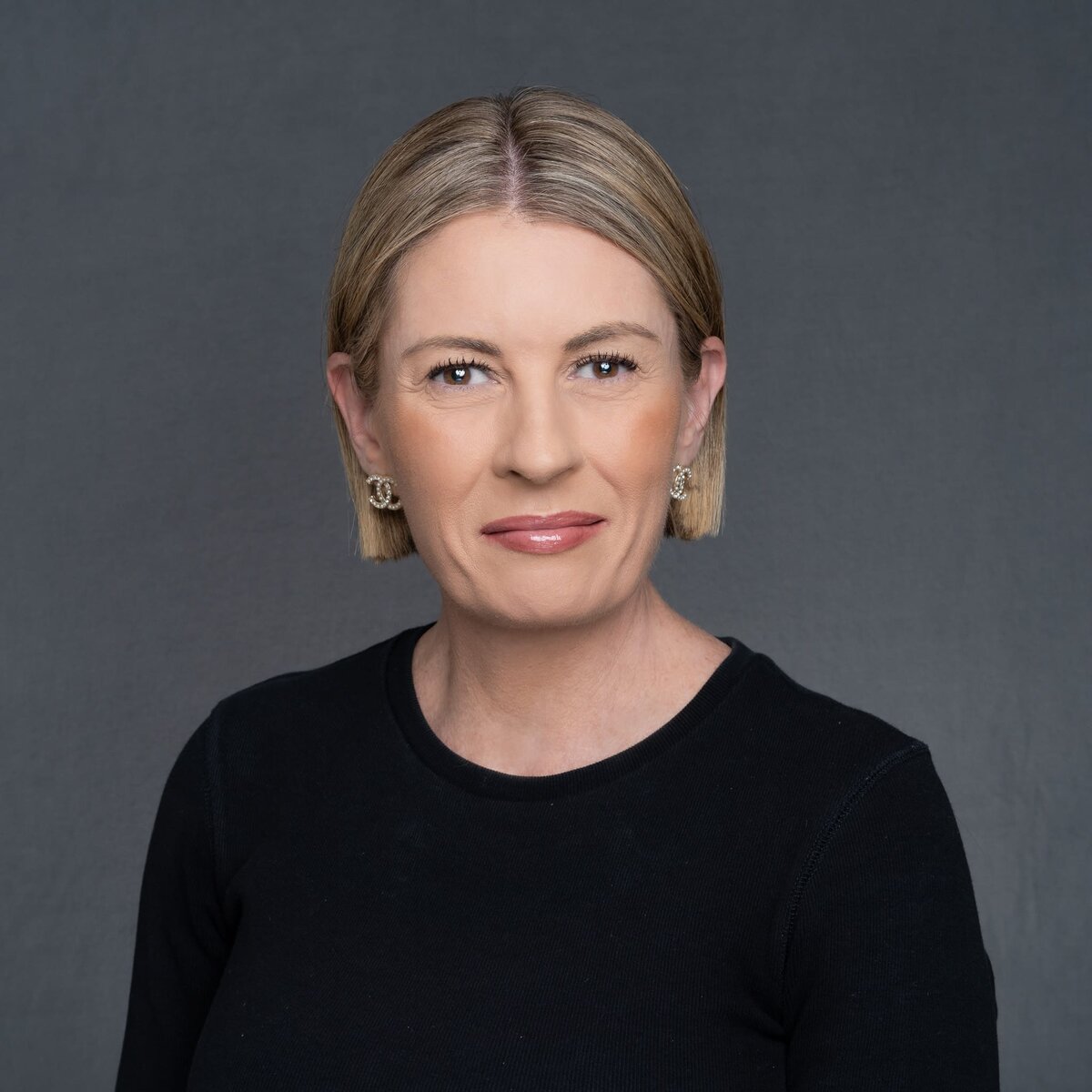 Blonde woman who is not smiling wearing a black top and having her headshot taken by Sydney headshot photographer Georgie Greene