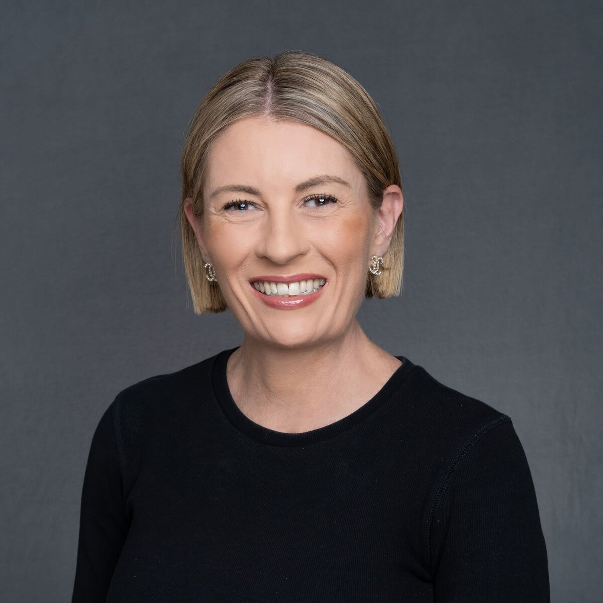 Smiling blonde woman wearing a black top and having her headshot taken by Sydney headshot photographer Georgie Greene