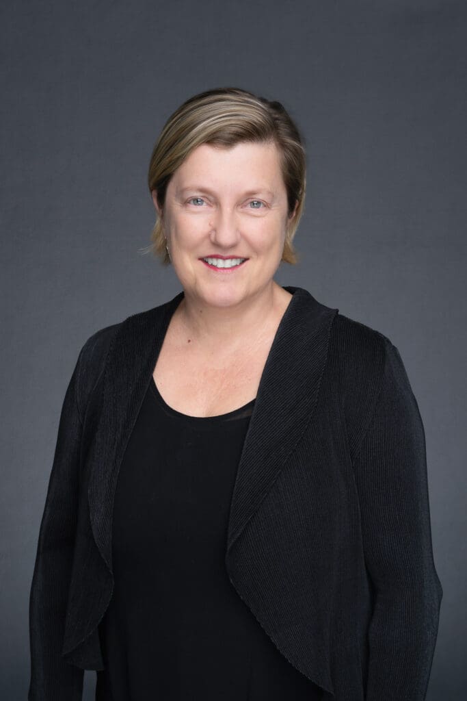 Older woman with blonde hair in a black blouse having her headshot taken by Sydney portrait photographer Georgie Greene