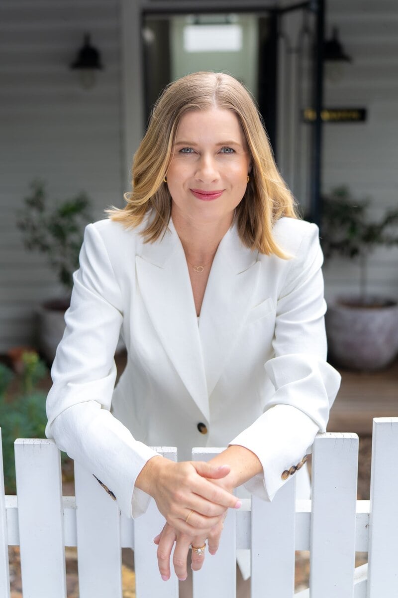 Woman in a white jacket leaning over a white fence having her personal branding taken by Sydney personal branding photographer Georgie Greene