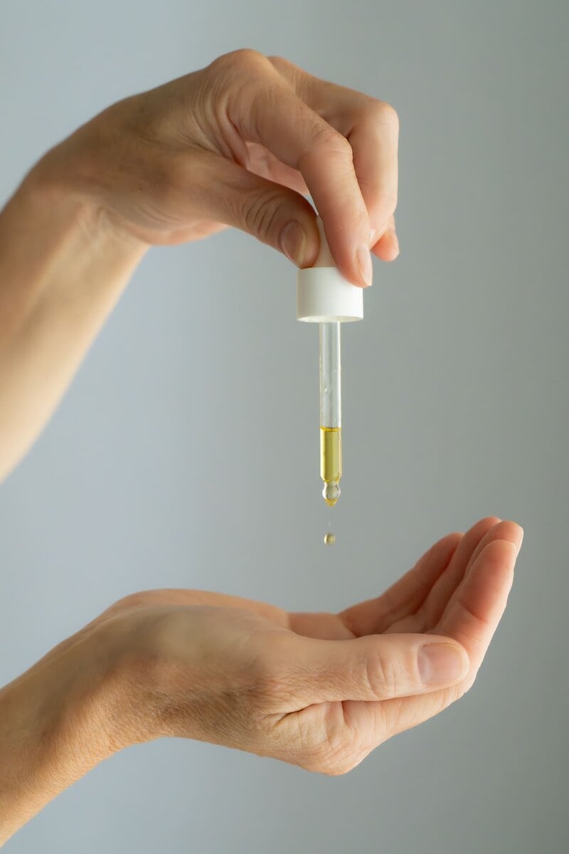 Hand hold a stopper of oil and squeezing a drop of oil into a hand