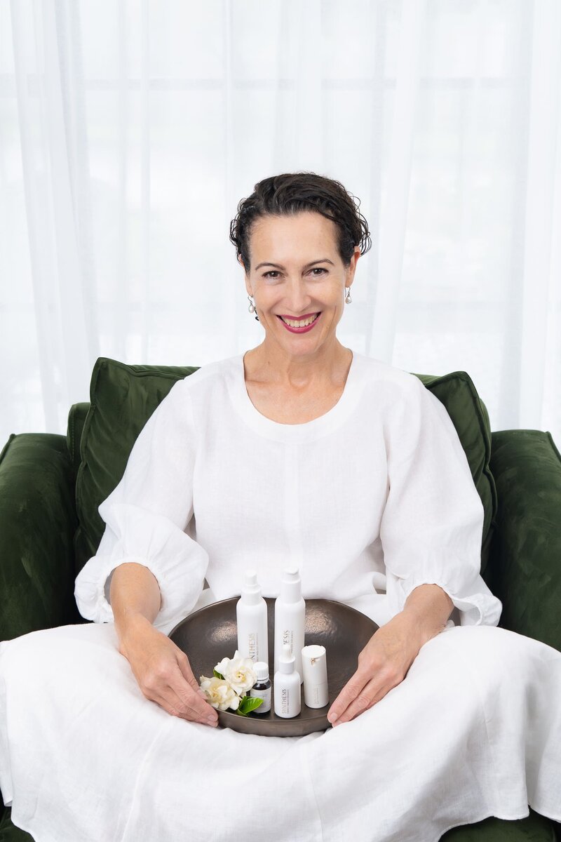 Beauty therapist wearing white and holding product in her lap as she has her personal branding photo taken by Sydney professional photographer Georgie Greene