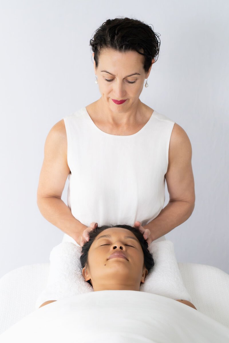Beauty therapist looking down at a client lying down as she has her personal branding photo taken by Sydney professional photographer Georgie Greene