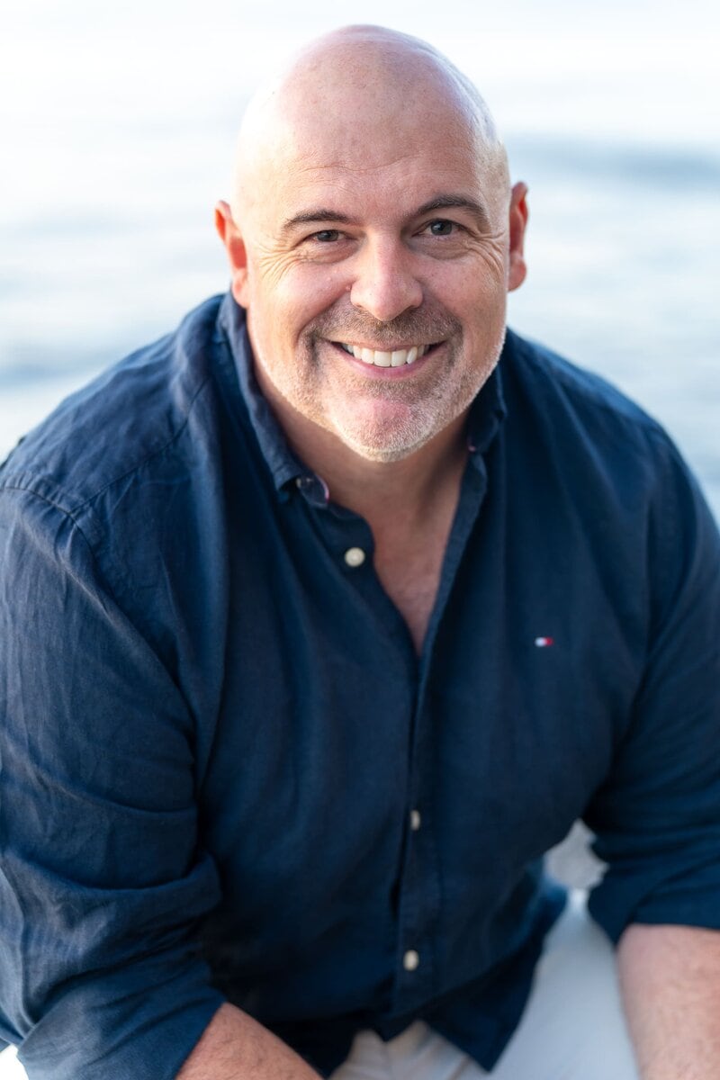 Bald man with a dark blue shirt sitting by the water having his dating photo taken by top Sydney dating photographer Georgie Greene