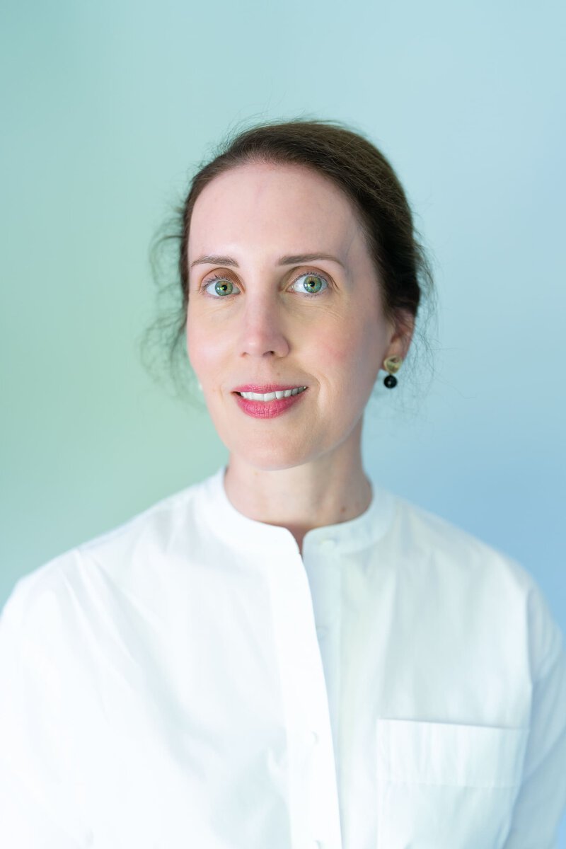Young dark haired woman wearing white shirt and having her natural light headshot taken by professional Sydney headshot photographer Georgie Greene